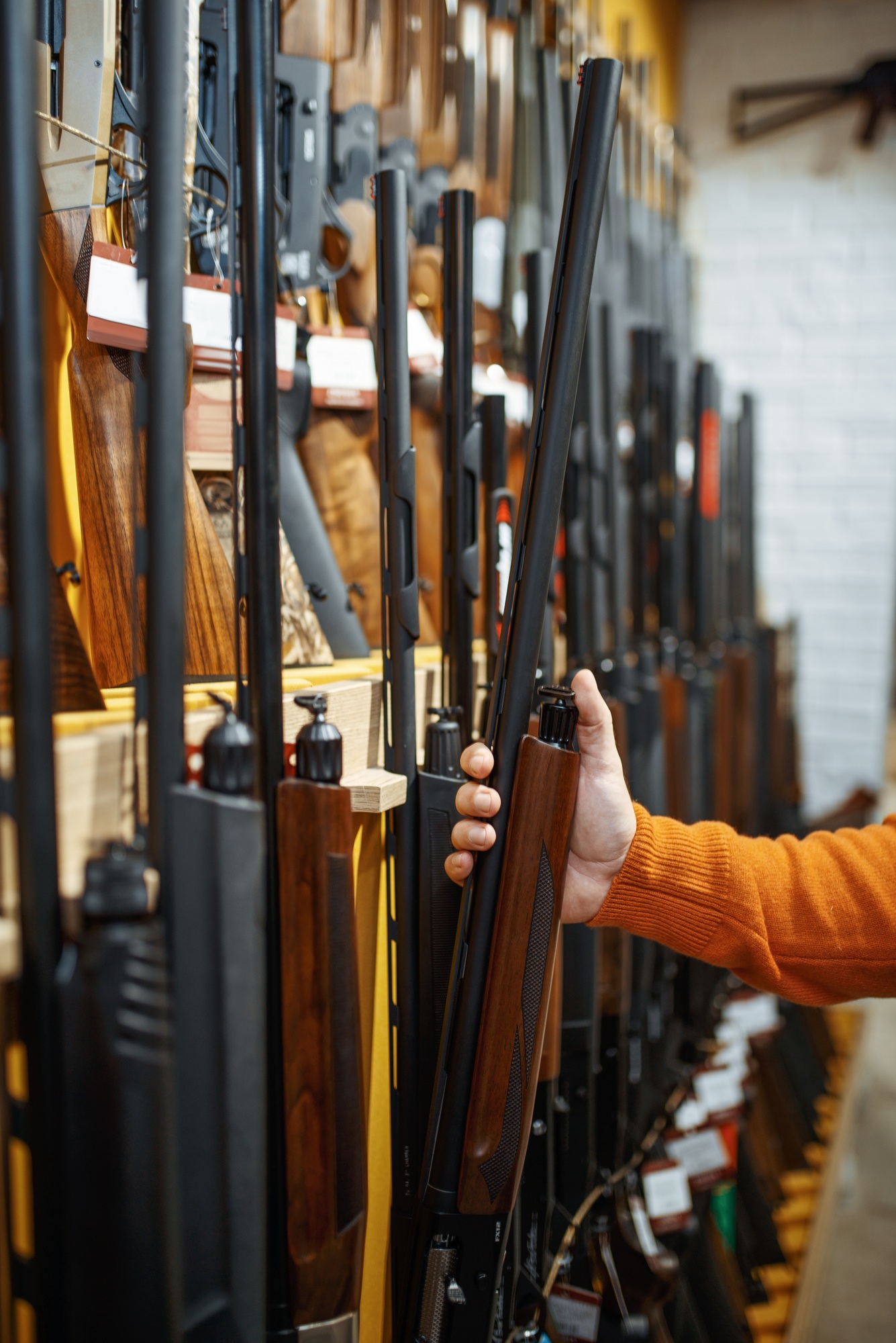 Man choosing rifle at showcase in gun shop